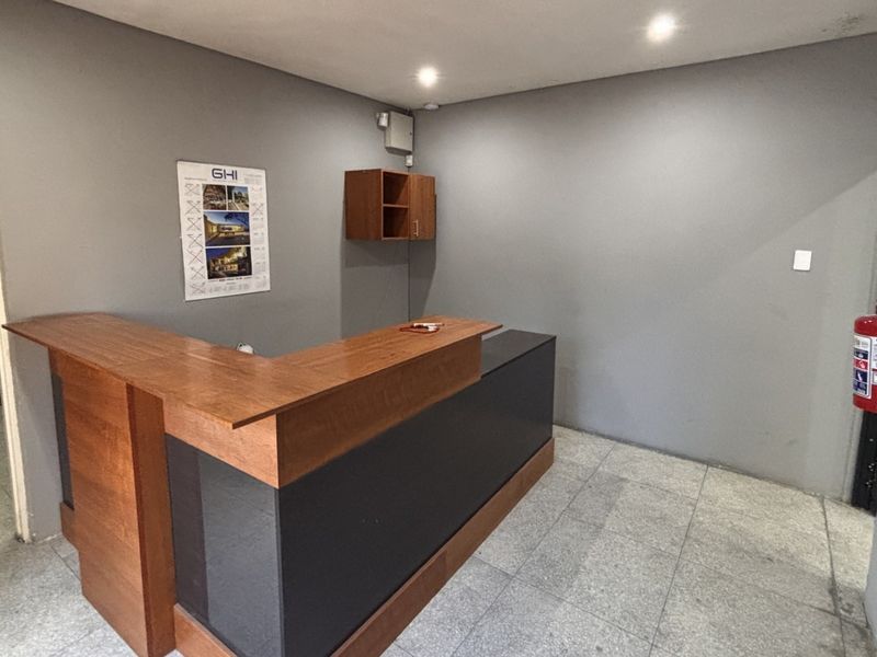 A functional industrial reception area featuring a built-in reception desk, tiled flooring, and recessed ceiling lighting.
