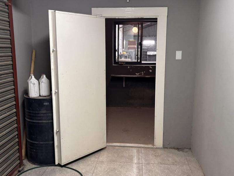 Utility space featuring a heavy-duty steel door, roller shutter access, and tiled flooring, suitable for secure storage or industrial workspace requirements.