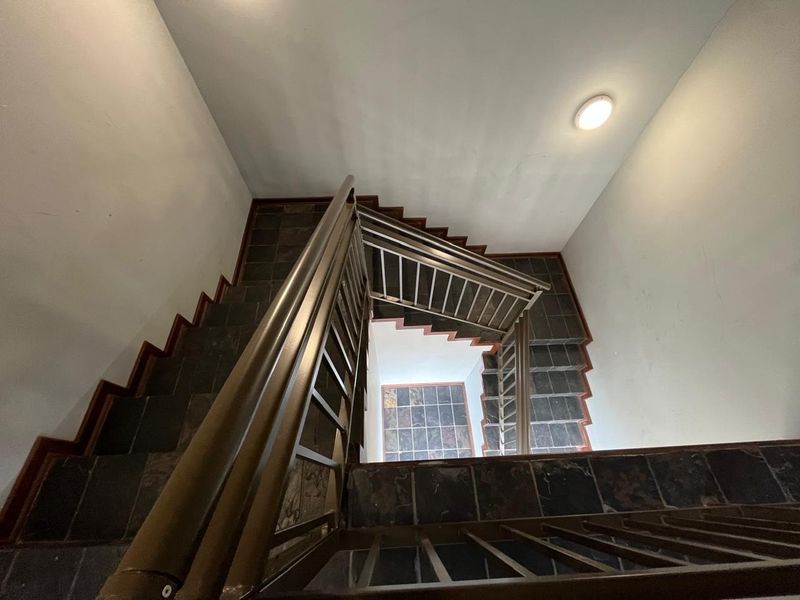 A multi-level staircase featuring dark tiled steps and a sturdy metal balustrade, providing vertical circulation within the building.