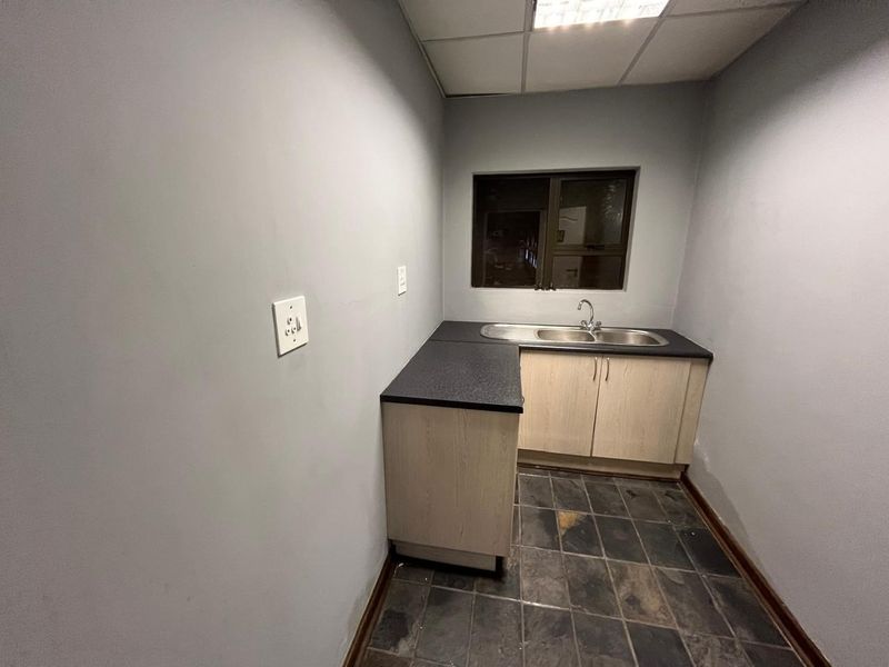 A functional scullery or kitchenette area featuring built-in cabinetry, a stainless steel sink, and tiled flooring, providing a practical utility space.