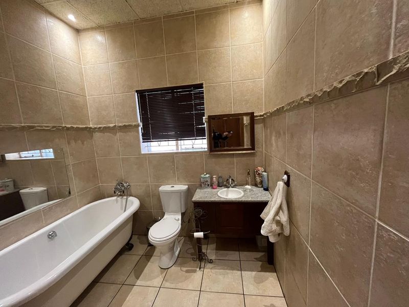 A functional bathroom featuring a freestanding bathtub, a vanity with a granite countertop, and full-height wall tiling.