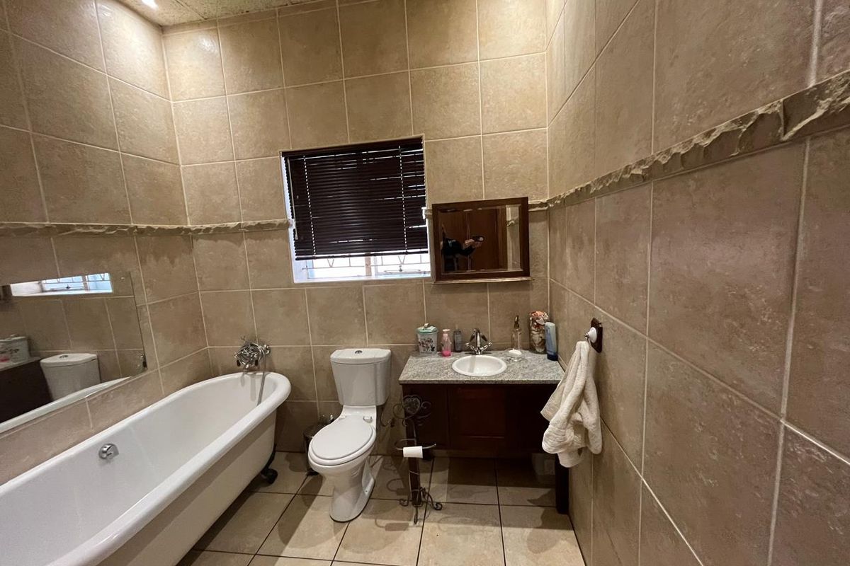 A functional bathroom featuring a freestanding bathtub, a vanity with a granite countertop, and full-height wall tiling.