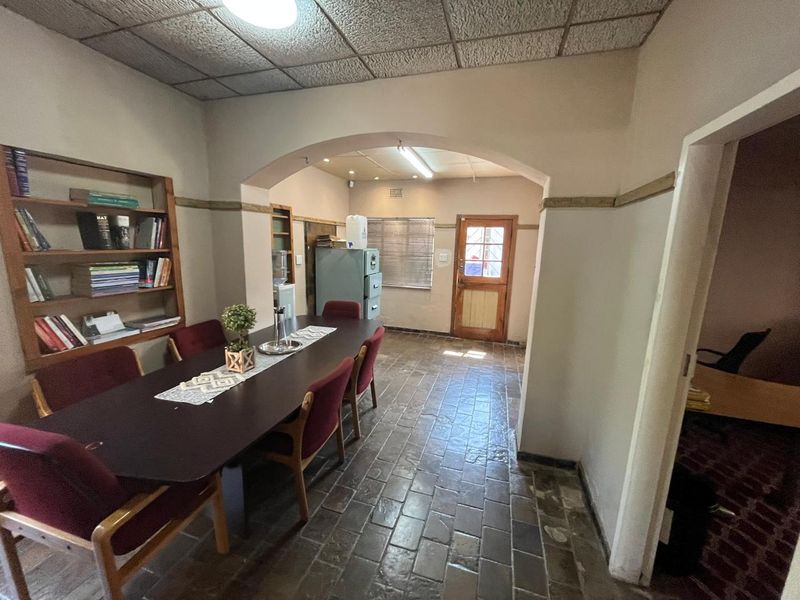 A functional office space featuring built-in shelving, tiled flooring, and a distinctive archway leading to an exterior access door.