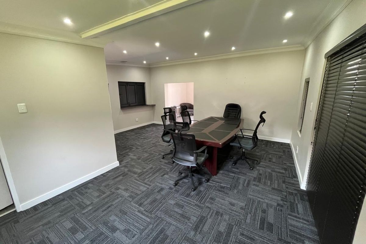 A professional office space featuring modern carpet tiles, recessed downlighting, and a convenient serving hatch, suitable for a meeting or workspace.