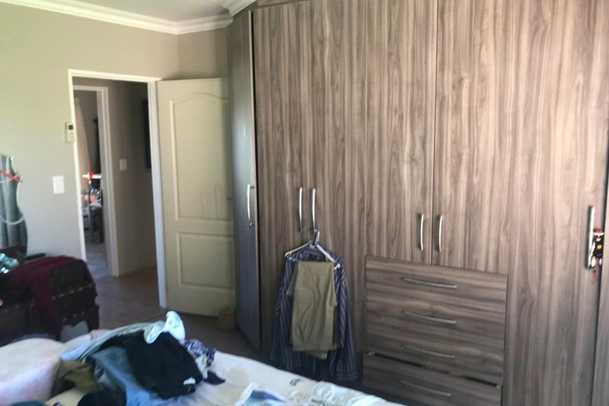 A bedroom featuring extensive wood-grain built-in cupboards with integrated drawers and classic coving detail.