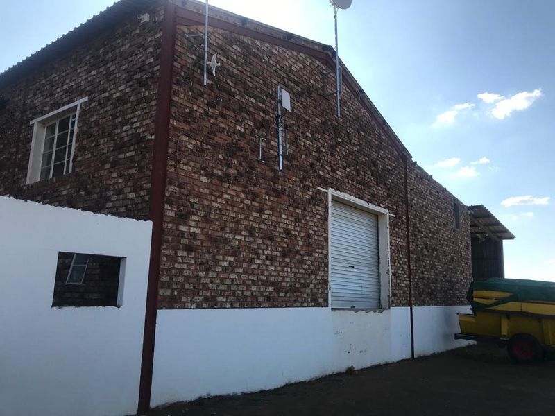 Rear view of a farm building featuring exposed brickwork, a roller shutter door, and steel structural elements.