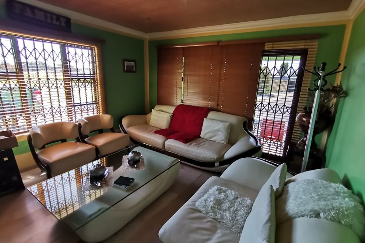 A living room featuring laminate flooring, a wooden ceiling with recessed lighting, and security gates on the windows and doors.