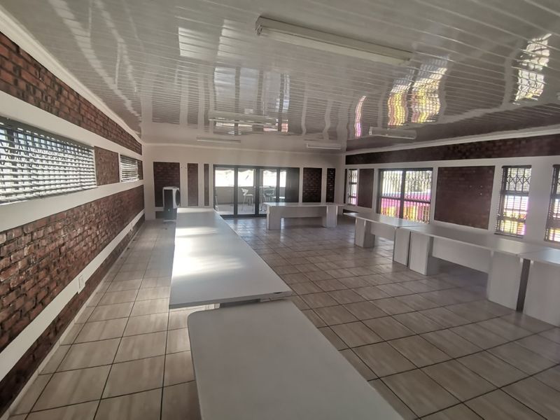 Spacious open-plan area featuring exposed brick walls, tiled flooring, and a PVC ceiling, suitable for a versatile workspace or large entertainment area.