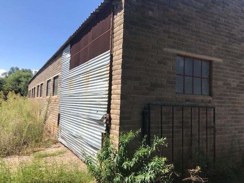 Rear view of a utilitarian brick and corrugated iron structure showing signs of weathering and maintenance requirements.