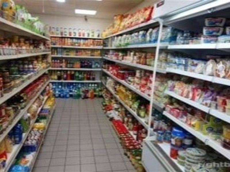 A retail utility space featuring fixed shelving units and refrigerated display cabinets, suitable for commercial inventory storage and product display.