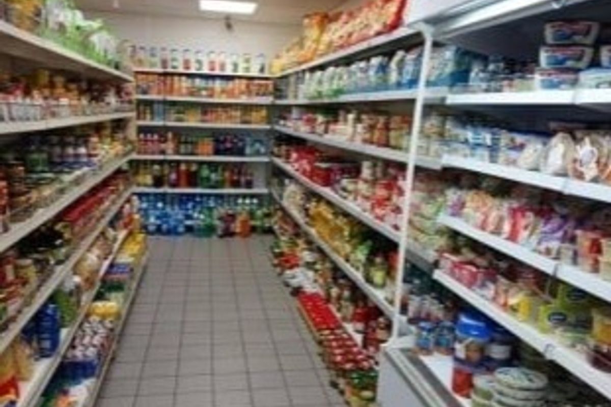 A retail utility space featuring fixed shelving units and refrigerated display cabinets, suitable for commercial inventory storage and product display.