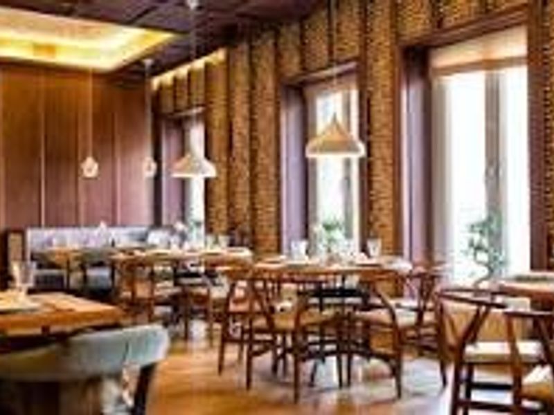 Elegant dining area featuring warm wood paneling, exposed brick walls, recessed ceiling lighting, and pendant fixtures, creating a sophisticated and inviting atmosphere.