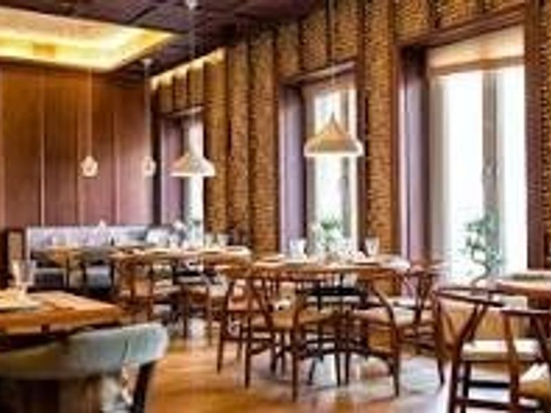 Elegant dining area featuring warm wood paneling, textured brick walls, hardwood flooring, and sophisticated pendant lighting, creating a refined atmosphere.