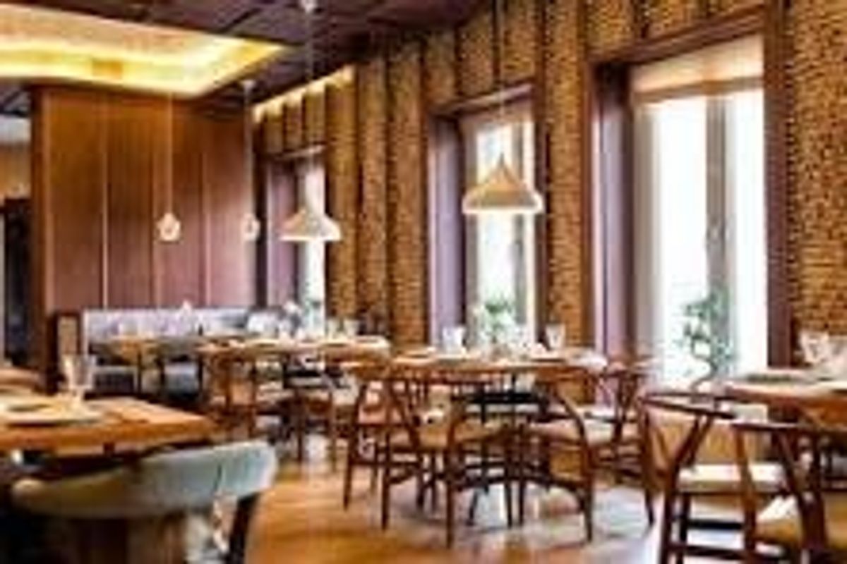 Elegant dining area featuring warm wood paneling, textured brick walls, hardwood flooring, and sophisticated pendant lighting, creating a refined atmosphere.