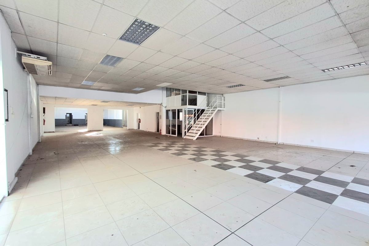 Spacious open-plan commercial area featuring a mezzanine level, metal staircase, suspended ceiling, and tiled flooring, suitable for various business or retail applications.