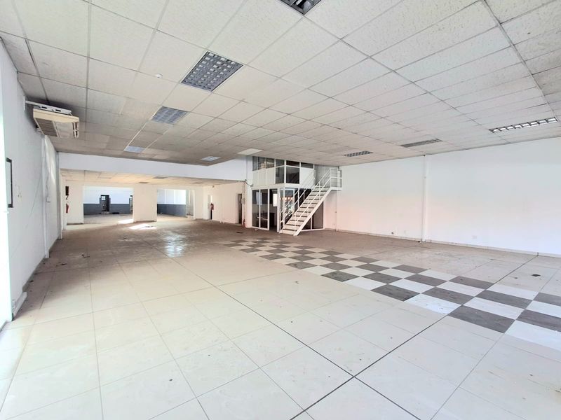 Spacious open-plan commercial area featuring a mezzanine level, metal staircase, suspended ceiling, and tiled flooring, suitable for various business or retail applications.