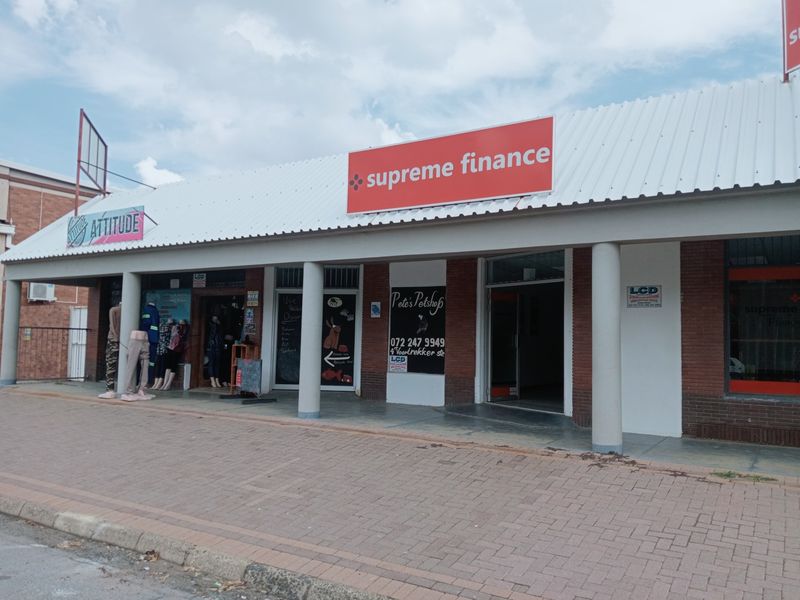 Front view of a commercial retail strip center featuring brick facade, concrete columns, and prominent signage for multiple business tenants.