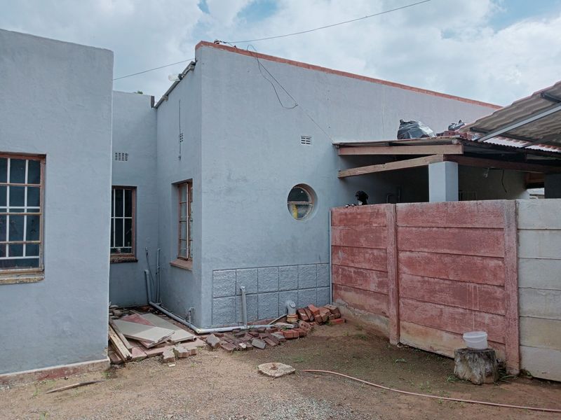 Rear exterior view of the commercial property showing a grey rendered facade, circular window, and a precast concrete boundary wall with an attached lean-to structure.