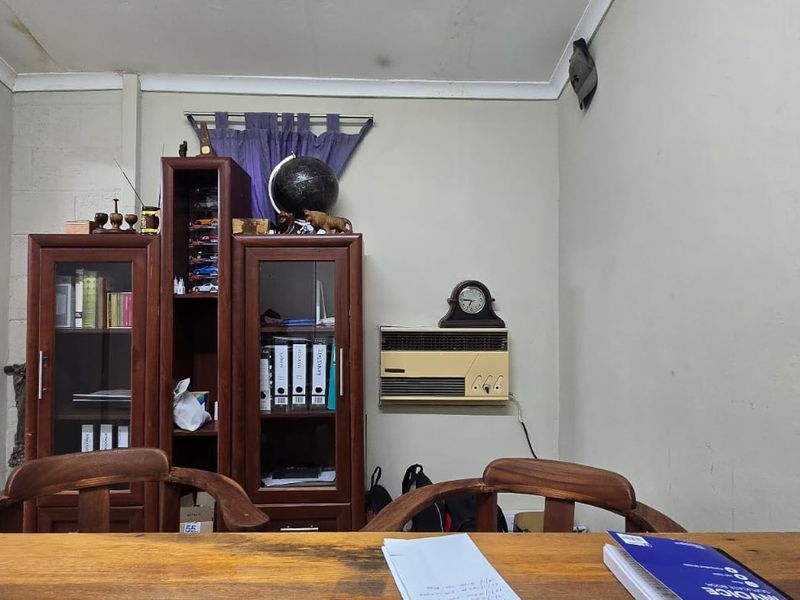 A functional office space featuring a wall-mounted air conditioning unit, coved ceiling details, and an arched entryway leading to adjacent areas.