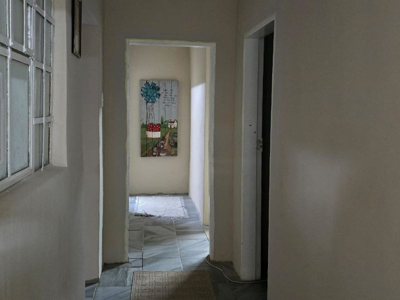 A functional interior hallway featuring tiled flooring and an internal window, providing access to adjacent rooms.