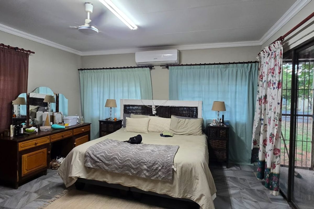 Spacious bedroom featuring tiled flooring, a split-system air conditioner, ceiling fan, and direct access to the exterior via a sliding glass door.