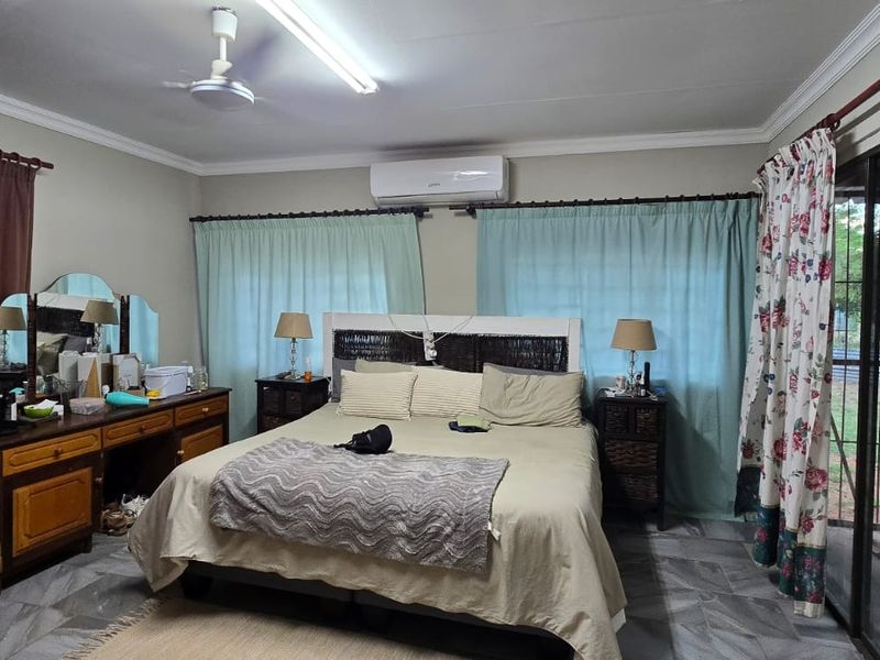 Spacious bedroom featuring tiled flooring, a split-system air conditioner, ceiling fan, and direct access to the exterior via a sliding glass door.