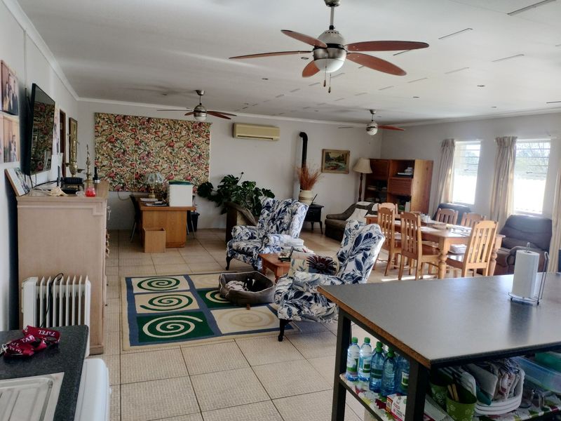 Spacious open-plan living and dining area featuring tiled flooring, multiple ceiling fans, a wood-burning stove, and split-system air conditioning.