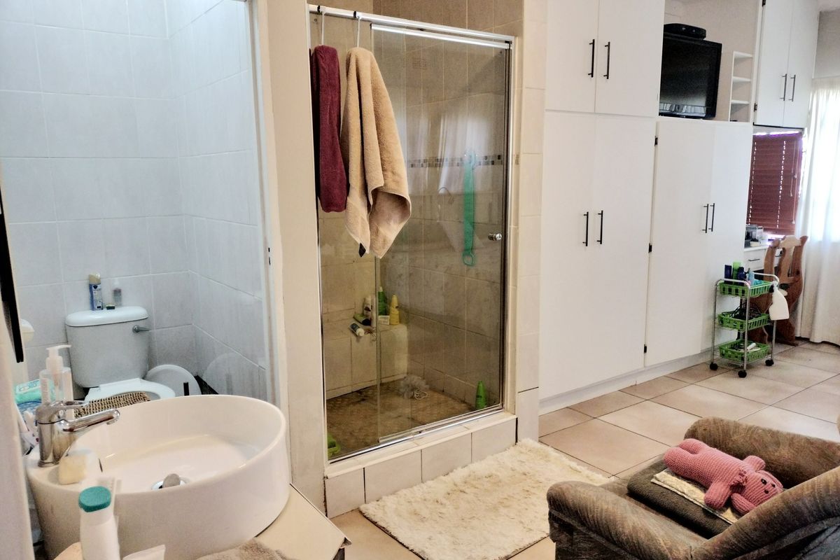A functional bathroom featuring a glass-enclosed shower, built-in storage cabinetry, and a modern vessel sink, with tiled flooring throughout.