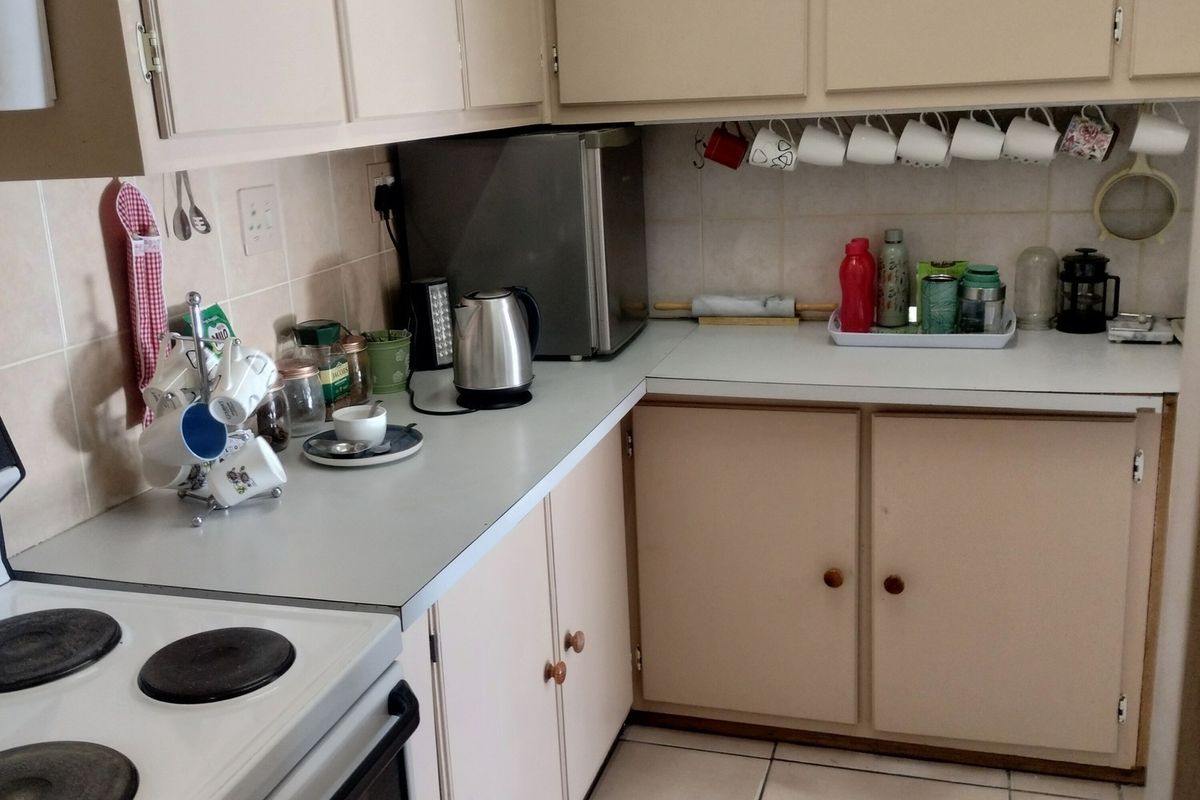 A functional kitchen featuring built-in cabinetry, laminate countertops, tiled backsplash, and ceramic tile flooring, providing a practical workspace for industrial or residential use.