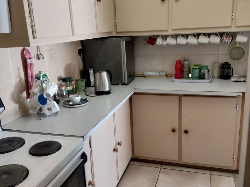 A functional kitchen featuring built-in cabinetry, laminate countertops, tiled backsplash, and ceramic tile flooring, providing a practical workspace for industrial or residential use.