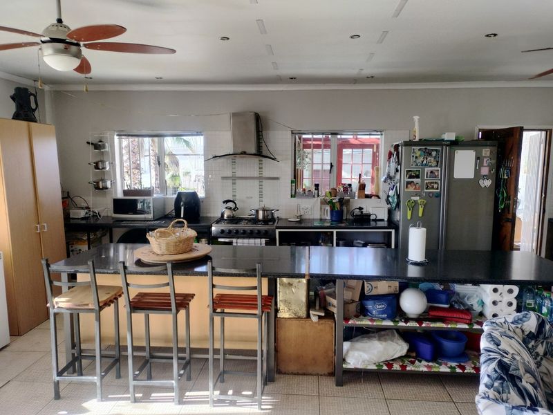 Functional kitchen featuring granite countertops, a gas stove with extractor fan, tiled backsplash, and a central island with integrated storage.