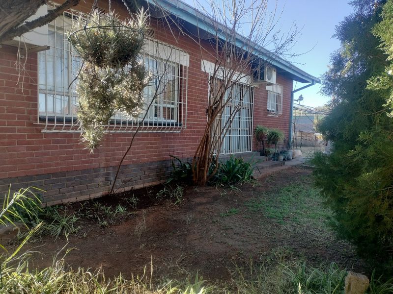 Rear exterior view of the industrial property featuring a face brick facade, security bars on windows, and an installed air conditioning unit.