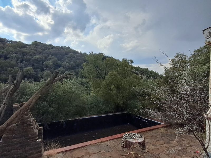 Outdoor stone patio area featuring a swimming pool with scenic hillside views, requiring maintenance and restoration of the pool structure.