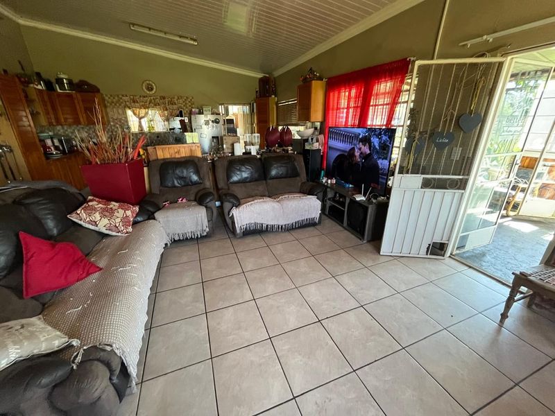 Open plan living area featuring tiled flooring, built-in kitchen cabinetry, and direct access to an outdoor patio through a security gate.