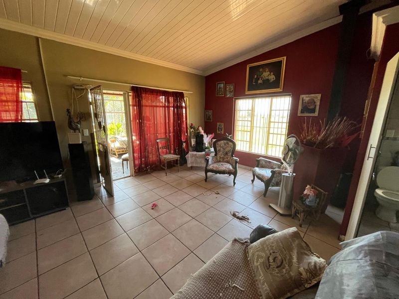 Spacious living area featuring tiled flooring, a wood-paneled ceiling, and a fireplace, with direct access to an outdoor patio area.