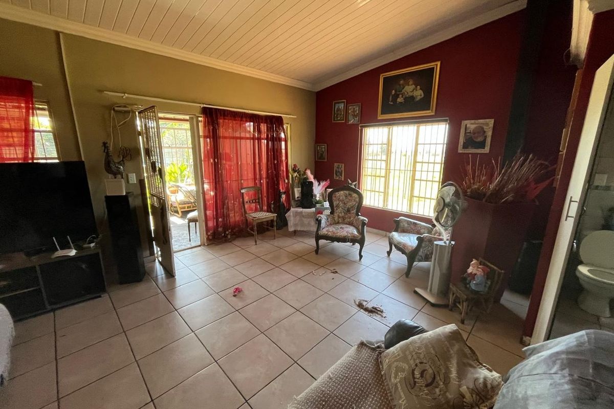 Spacious living area featuring tiled flooring, a wood-paneled ceiling, and a fireplace, with direct access to an outdoor patio area.
