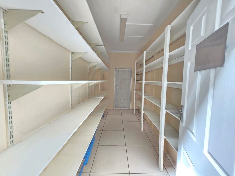 A functional utility or storage room featuring extensive built-in shelving, tiled flooring, and a secure access door.