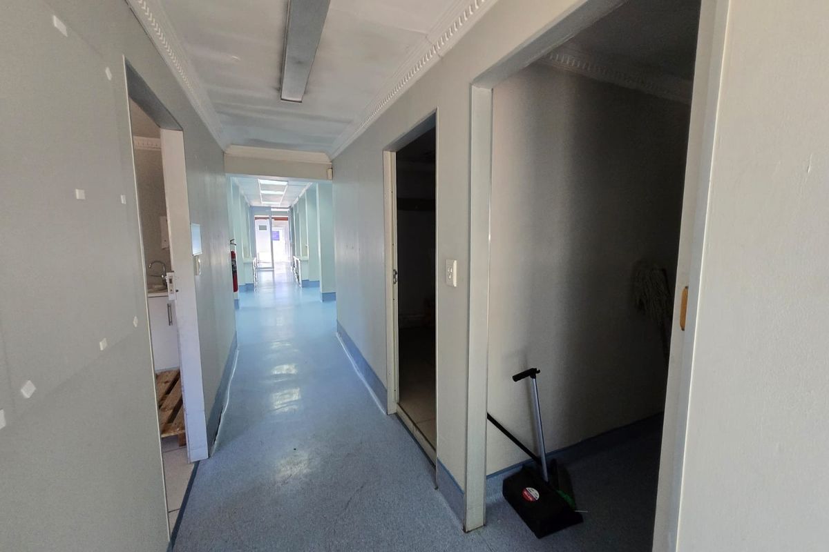A long commercial hallway featuring vinyl flooring and fluorescent lighting, providing access to multiple rooms within the property.