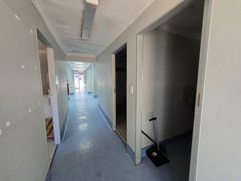 A long commercial hallway featuring vinyl flooring and fluorescent lighting, providing access to multiple rooms within the property.