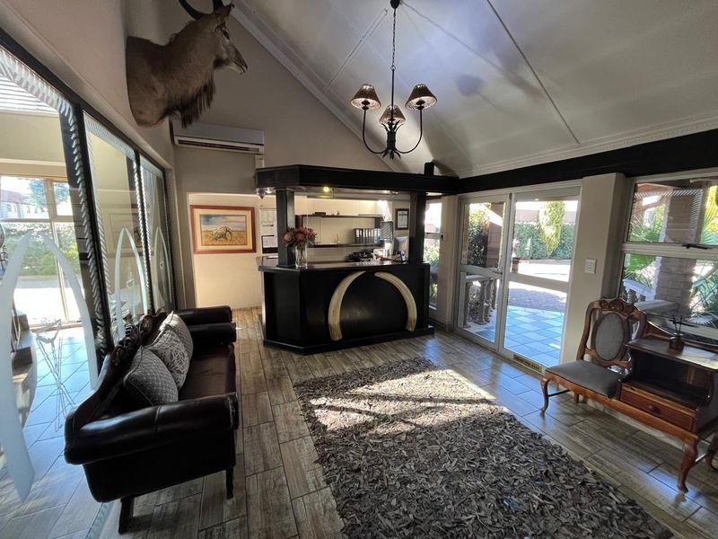 A welcoming guest house reception area featuring a built-in desk, vaulted ceilings, tiled flooring, and direct access to the exterior through glass sliding doors.