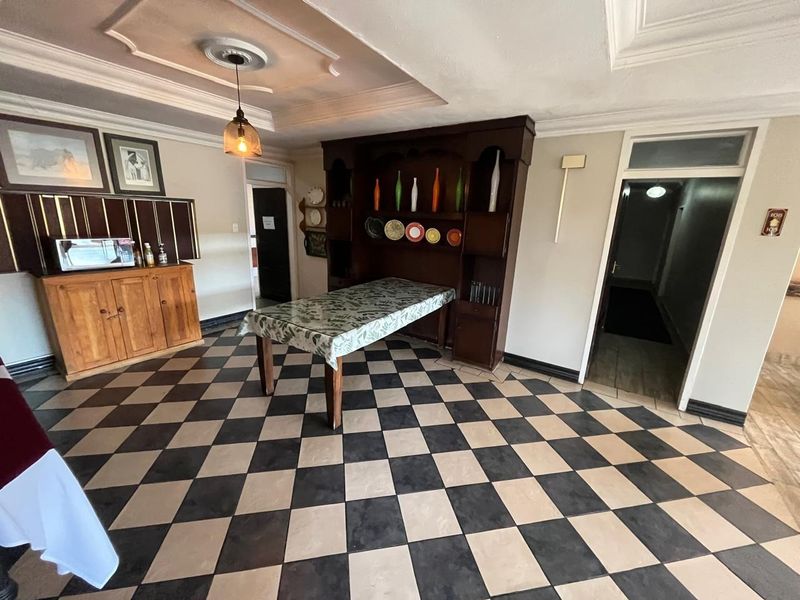 Dining area featuring classic checkered tile flooring, decorative ceiling molding, and built-in wooden cabinetry, offering a traditional aesthetic with potential for modern updates.