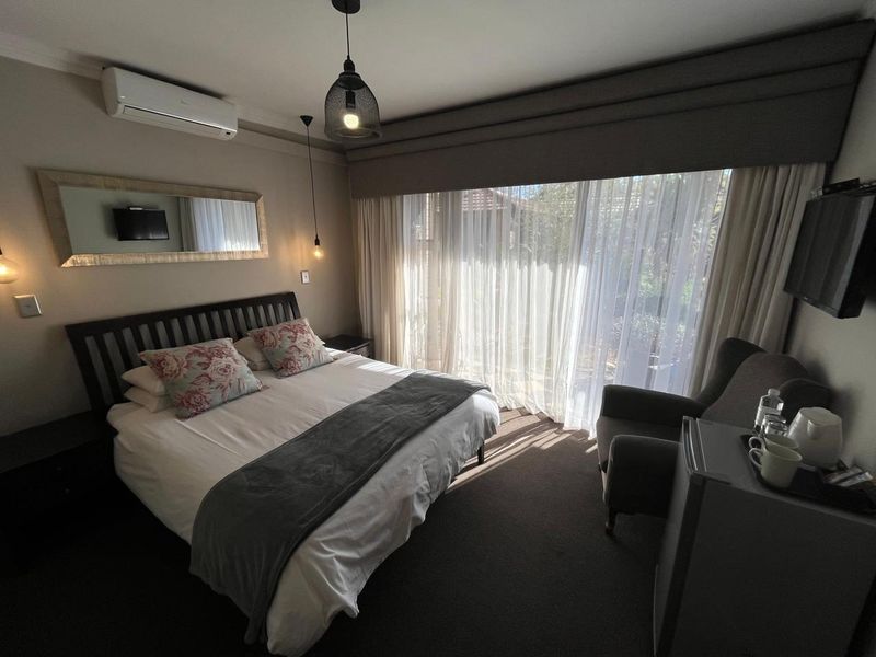 A well-maintained bedroom featuring a split-system air conditioner, pendant lighting, and large sliding glass doors with integrated curtain pelmets for natural light control.