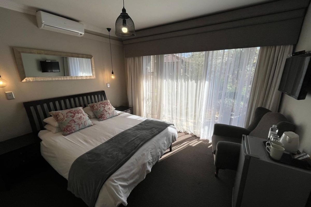A well-maintained bedroom featuring a split-system air conditioner, pendant lighting, and large sliding glass doors with integrated curtain pelmets for natural light control.