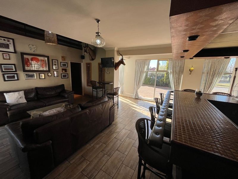 Spacious open-plan living area featuring a built-in bar counter, tiled flooring, and large sliding glass doors providing access to the exterior.