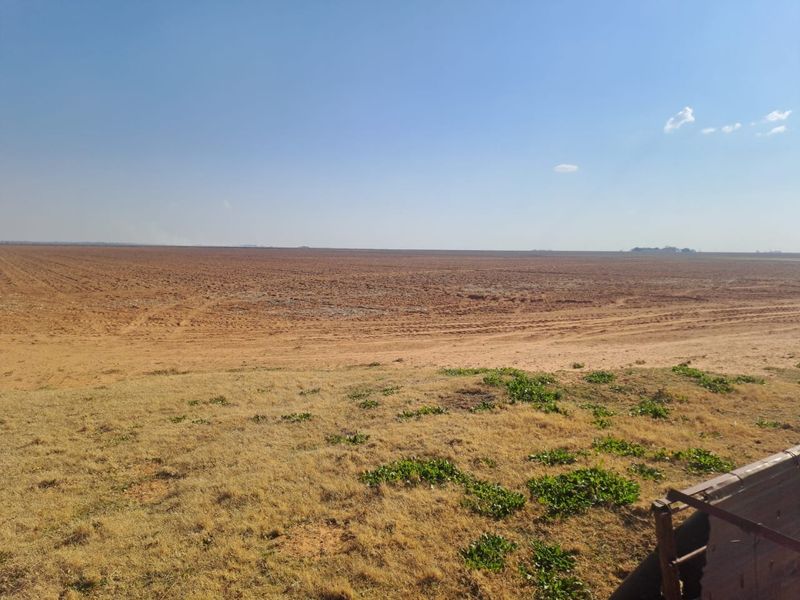 A wide-angle view of expansive, tilled agricultural land on the farm, showcasing the open landscape and soil preparation.