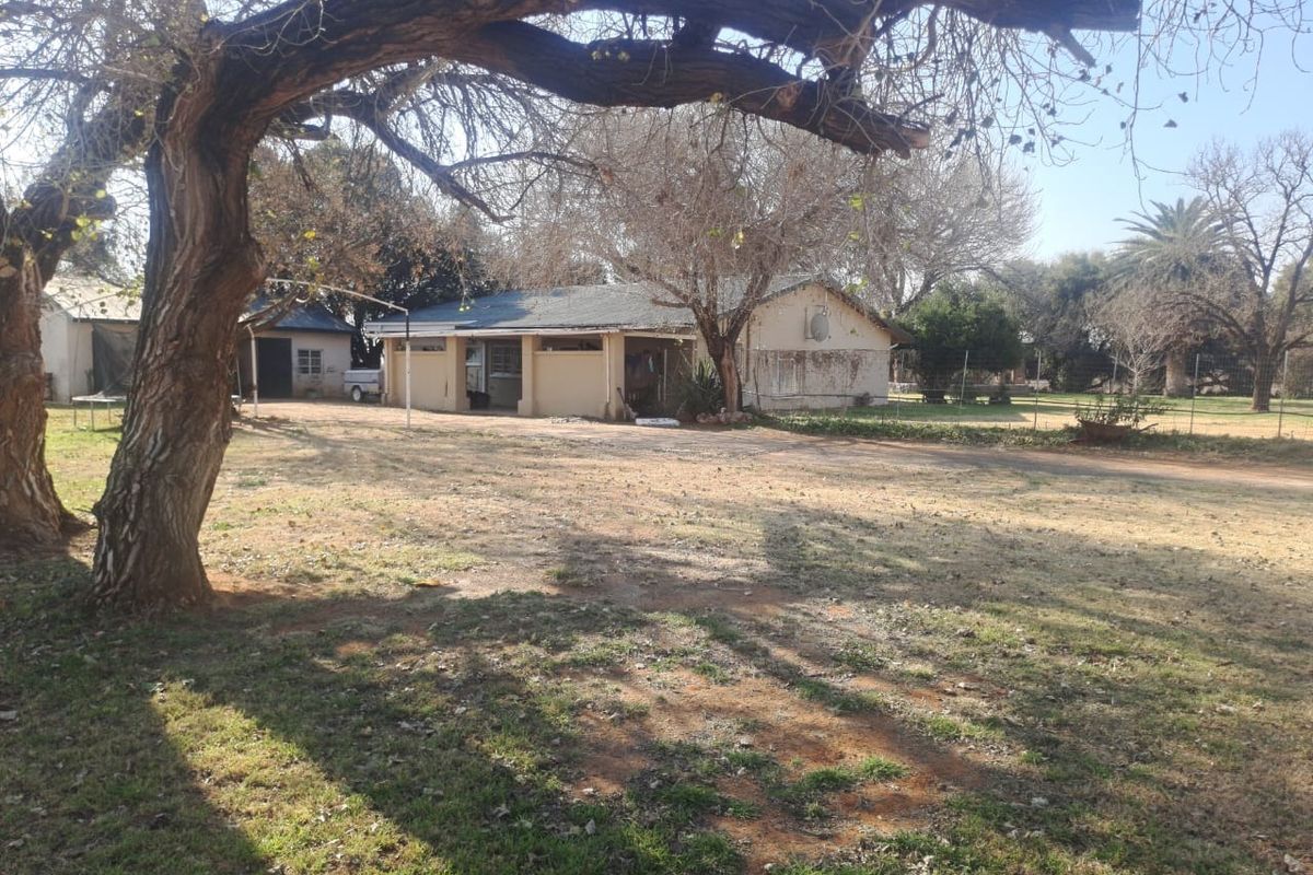 Rear view of the farm property showing the main dwelling with a covered patio area and surrounding garden space.