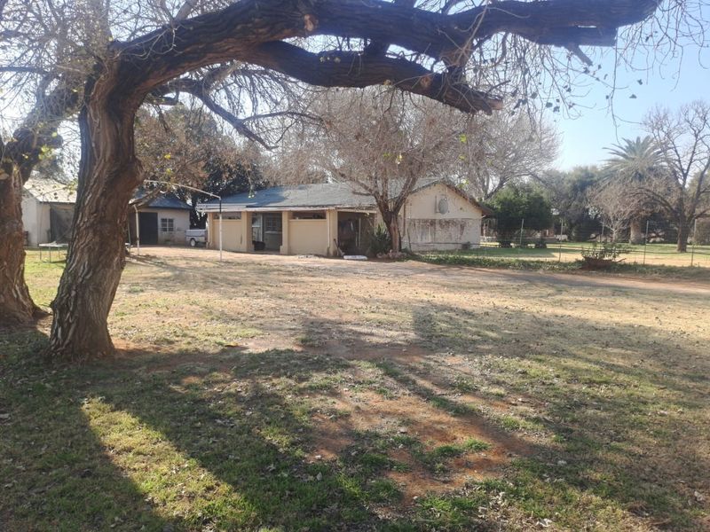 Rear view of the farm property showing the main dwelling with a covered patio area and surrounding garden space.