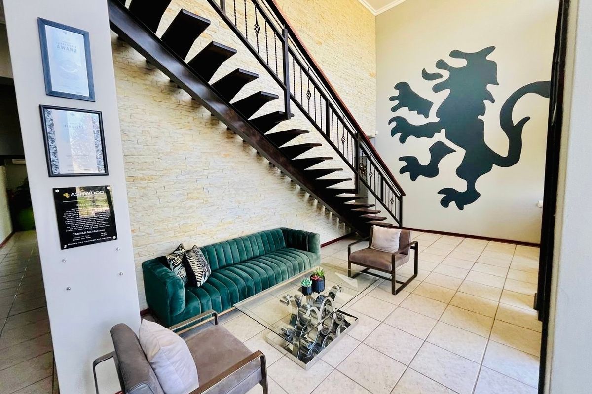 Spacious entrance hall featuring a striking staircase with a wrought iron balustrade, stone feature wall, and neutral ceramic floor tiles.