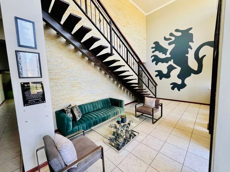 Spacious entrance hall featuring a striking staircase with a wrought iron balustrade, stone feature wall, and neutral ceramic floor tiles.