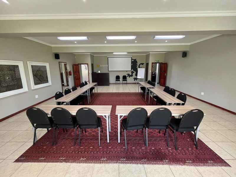 A spacious conference or meeting room featuring tiled flooring, recessed lighting, and a built-in projection screen, suitable for professional gatherings and events.